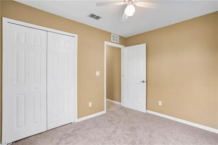 Unfurnished bedroom with light colored carpet, a closet, and ceiling fan