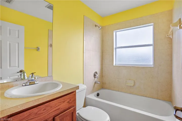 Full bathroom with tiled shower / bath combo, vanity, and toilet