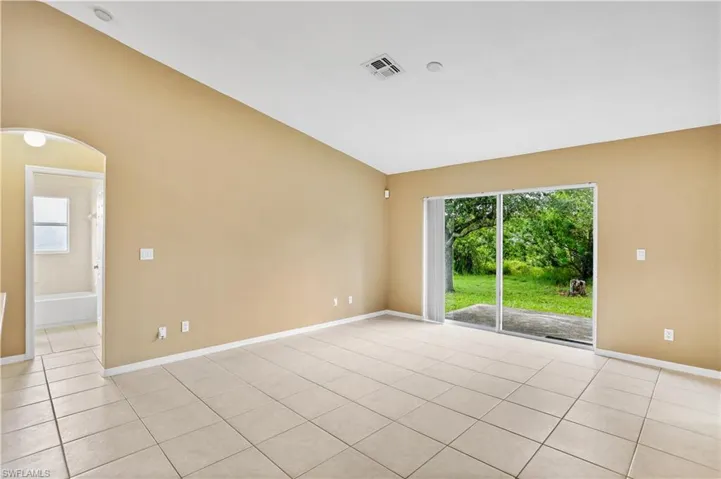 Spare room featuring lofted ceiling and light tile floors