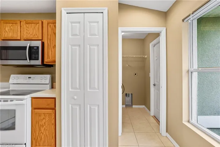 Kitchen with vaulted ceiling, electric stove, and light tile flooring