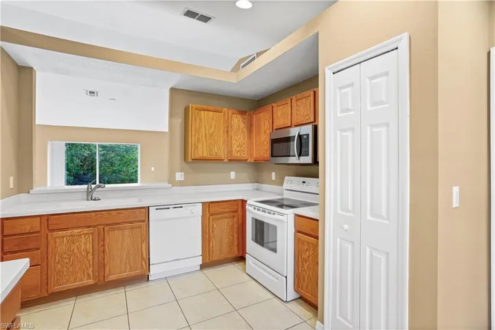 Kitchen featuring sink, white appliances, and light tile floors