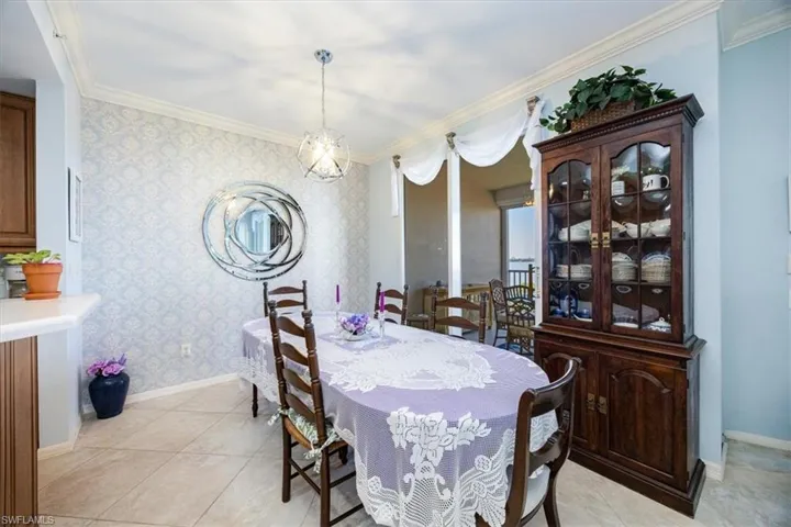 Tiled dining space featuring crown molding