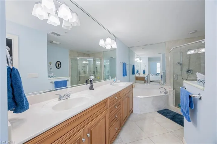 Bathroom featuring tile patterned flooring, vanity, and separate shower and tub