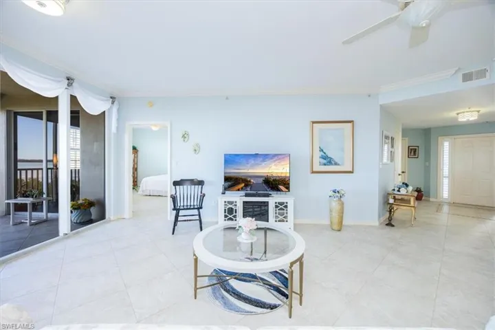 Tiled living room with ceiling fan and ornamental molding
