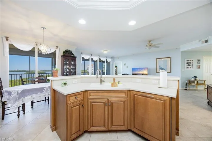 Kitchen featuring sink, ceiling fan with notable chandelier, decorative light fixtures, and ornamental molding