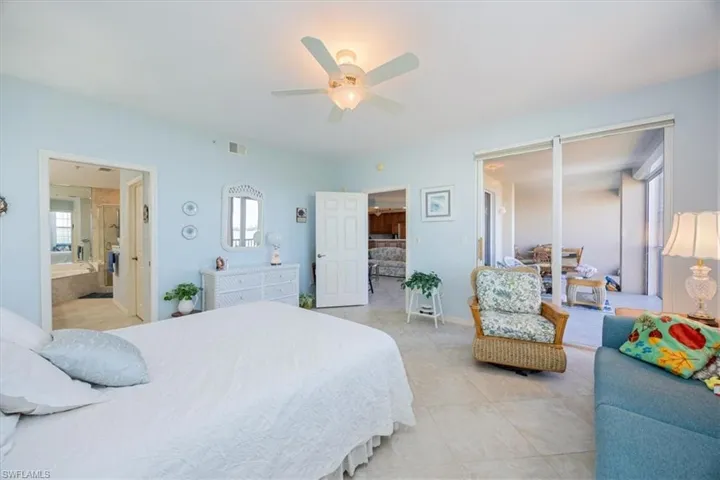 Bedroom with ceiling fan, light tile patterned floors, and ensuite bath