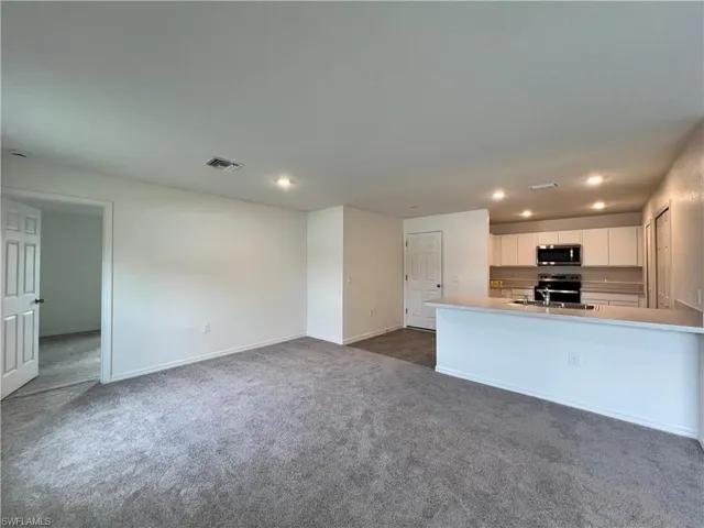 Unfurnished living room with recessed lighting and dark colored carpet