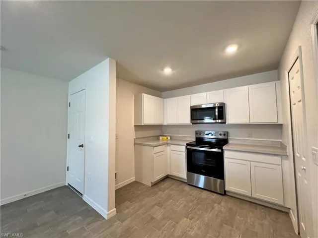 Kitchen featuring stainless steel appliances, white cabinets, light countertops, wood tiled floors, and recessed lighting