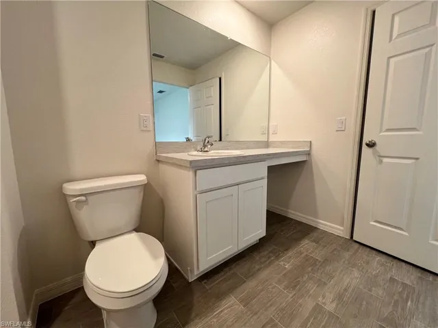 Bathroom featuring vanity, wood finish floors, and a textured wall