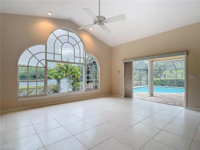 Great Room with large ornate window, vaulted ceiling, pocket sliders to the screened-in lanai, and an abundance of natural light