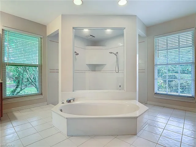 Spacious Master Bathroom featuring a sunk-in bathtub, large open shower, water closet, and two vanities.