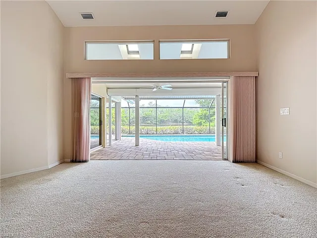 Spacious Living room featuring large pocket sliders opening to the lanai and pool, vaulted ceilings, and a view of the water and preserve.