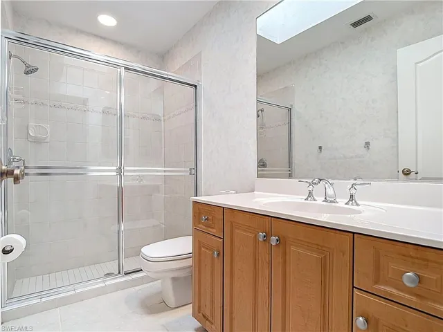 Full bathroom with vanity, a stall shower, a skylight, and tile patterned flooring