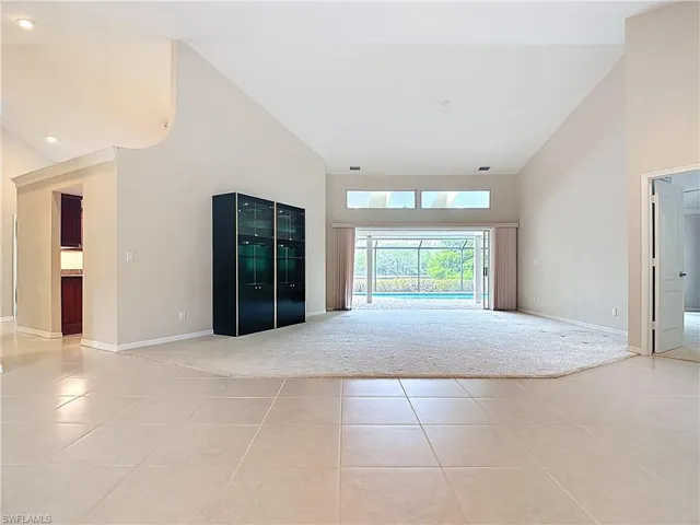 Spacious Living room featuring large pocket sliders opening to the lanai and pool, vaulted ceilings, and a view of the water and preserve.