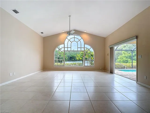 Great Room with large ornate window, vaulted ceiling, pocket sliders to the screened-in lanai, and an abundance of natural light
