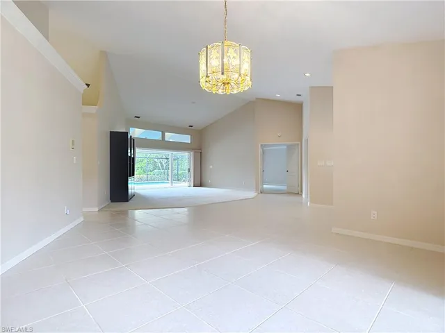 Spacious Living room featuring large pocket sliders opening to the lanai and pool, vaulted ceilings, and a view of the water and preserve.