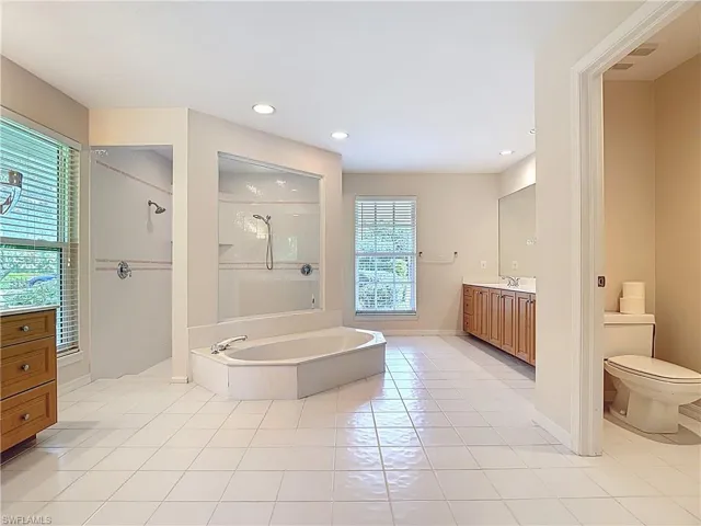 Spacious Master Bathroom featuring a sunk-in bathtub, large open shower, water closet, and two vanities.