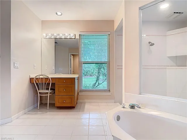 Spacious Master Bathroom featuring a sunk-in bathtub, large open shower, water closet, and two vanities.