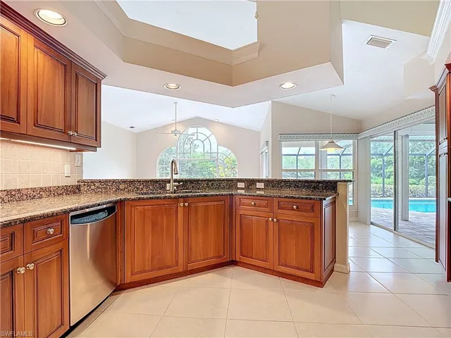 Kitchen featuring chestnut style cabinetry, vaulted ceiling, dishwasher, and recessed lighting