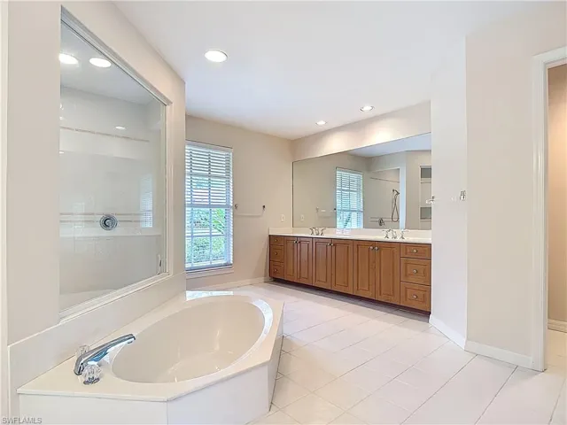 Spacious Master Bathroom featuring a sunk-in bathtub, large open shower, water closet, and two vanities.