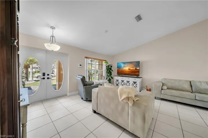 Living area featuring light tile patterned flooring, vaulted ceiling, and french doors