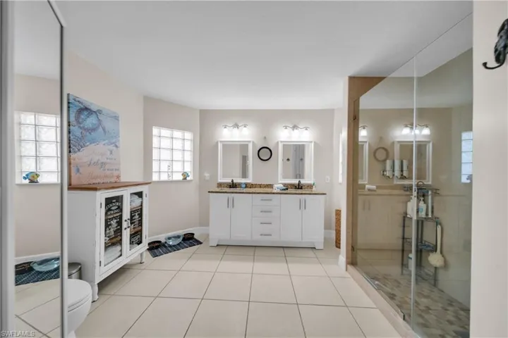 Bathroom with double vanity, light tile patterned floors, and a shower stall