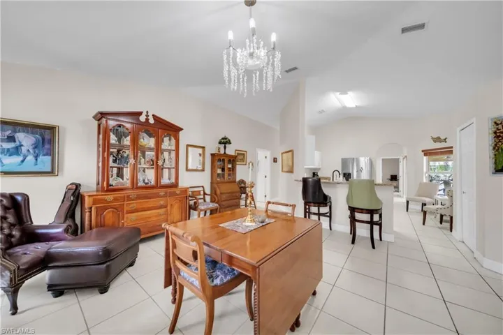 Dining space with lofted ceiling, hanging lights, light tile patterned floors, and arched walkways