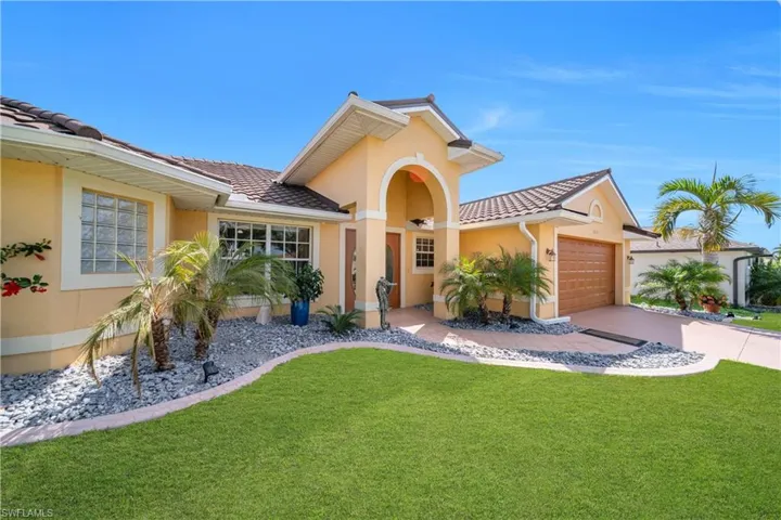 Mediterranean / spanish home with a front lawn, an attached garage, a tile roof, and stucco siding