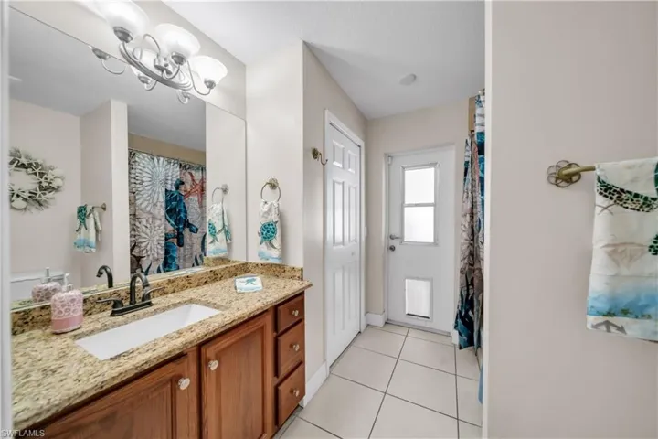 Full bath with vanity, a shower with curtain, light tile patterned flooring, and suspended lighting