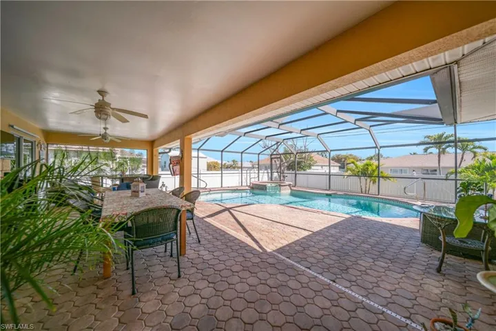 Integrated pool / spa with a sunroom, a patio, a lanai, a fenced backyard, and outdoor dining space