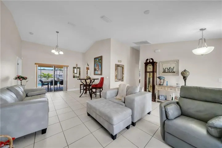 Living area with lofted ceiling, light tile patterned flooring, and suspended lighting