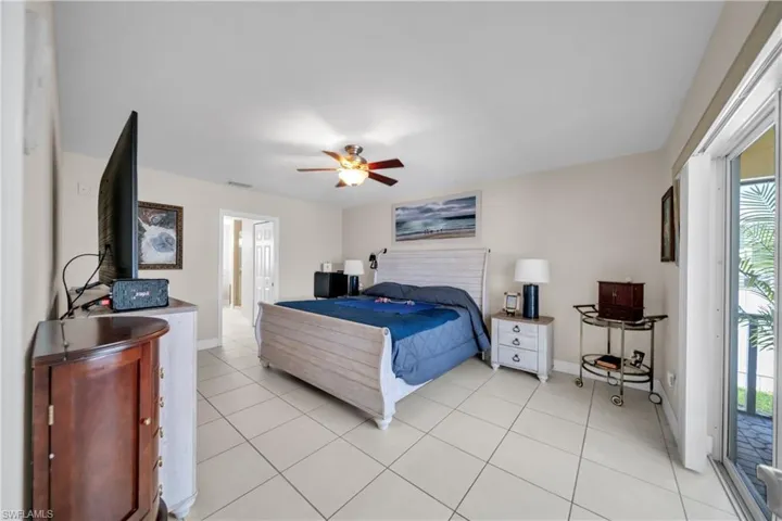 Bedroom with access to exterior, a ceiling fan, and light tile patterned floors