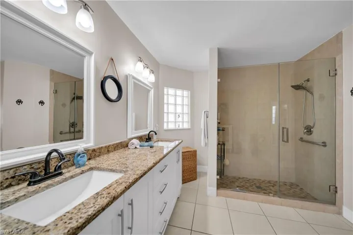 Full bath featuring double vanity, a shower stall, and light tile patterned flooring