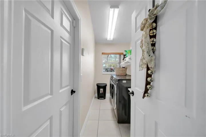 Laundry room with independent washer and dryer and light tile patterned flooring