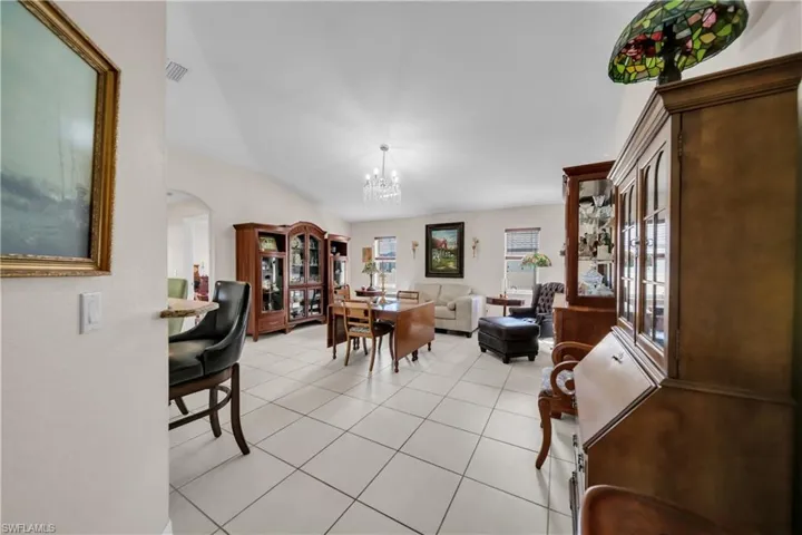 Dining area featuring arched walkways, suspended lighting, and light tile patterned flooring