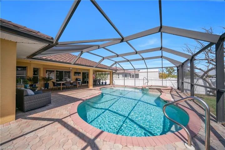 Combined pool / hot tub with an outdoor living / dining area, a sunroom, a fenced backyard, glass enclosure, and a patio area