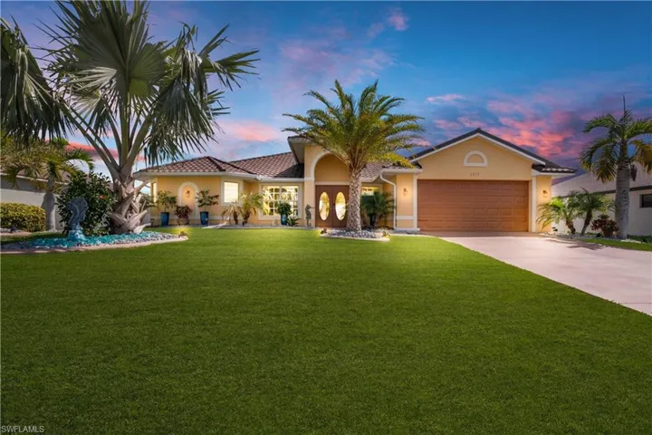 Mediterranean / spanish house featuring an attached garage, driveway, stucco siding, and a front yard