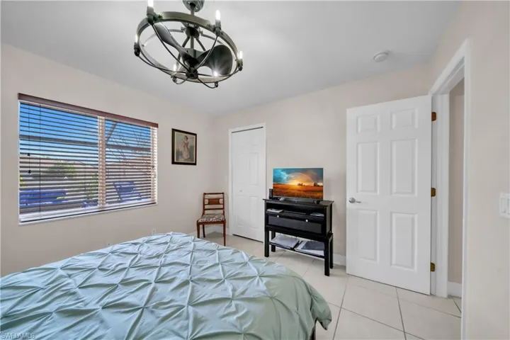 Bedroom featuring suspended lighting, light tile patterned floors, and a closet