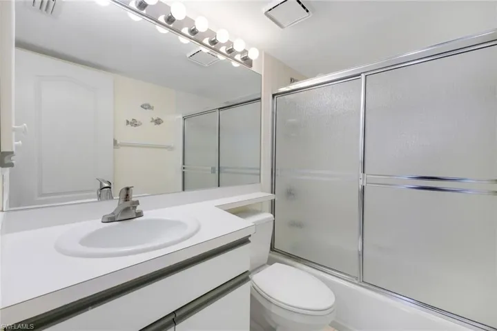 Full bathroom featuring bath / shower combo with glass door, vanity, and toilet
