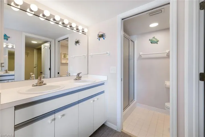 Bathroom featuring toilet, vanity, a shower with shower door, and tile patterned floors
