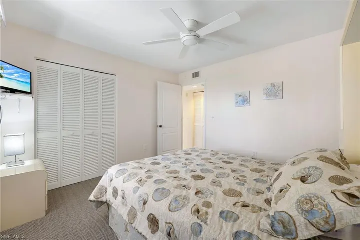 Carpeted bedroom featuring ceiling fan and a closet