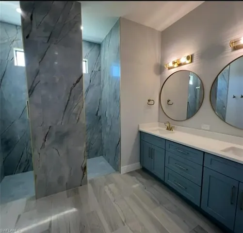 Bathroom with double vanity and a marble finish shower