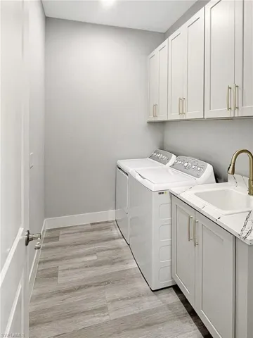 Laundry area featuring cabinet space, independent washer and dryer, and light wood-style floors