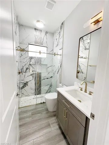 Full bath featuring a marble finish shower and vanity