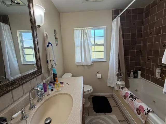 Bathroom featuring vanity, light tile patterned floors, and a combined bath / shower with jetted tub