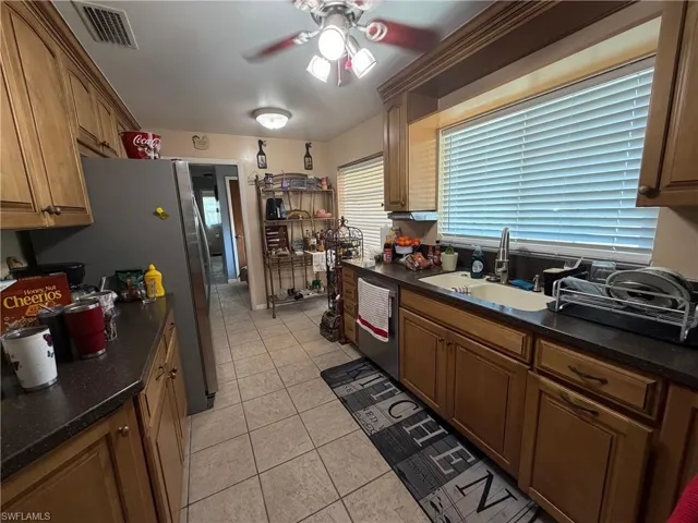 Kitchen with a ceiling fan, Quarts countertops, stainless steel appliances, light tile patterned floors, and wood finish cabinets