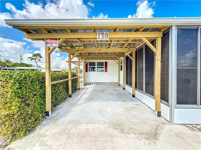 View of patio / terrace with an attached carport, driveway, and a sunroom