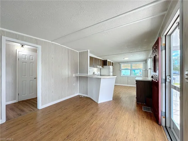 Kitchen with light wood finished floors, visible vents, a peninsula, and freestanding refrigerator
