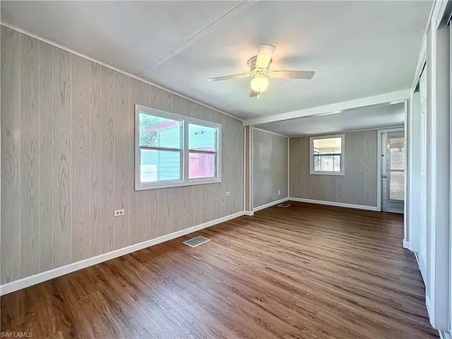 Unfurnished room featuring a ceiling fan, visible vents, wood finished floors, and baseboards