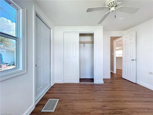 Unfurnished bedroom with visible vents, dark wood-type flooring, a closet, baseboards, and ceiling fan